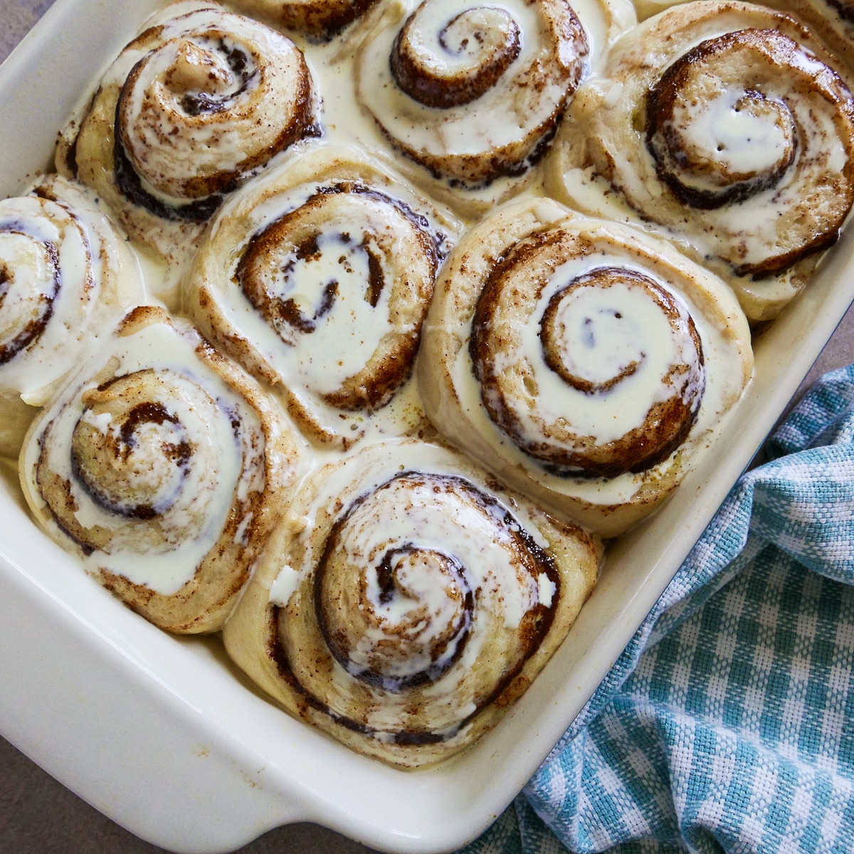 heavy cream poured on top of rolls in a baking dish with napkin next to them.