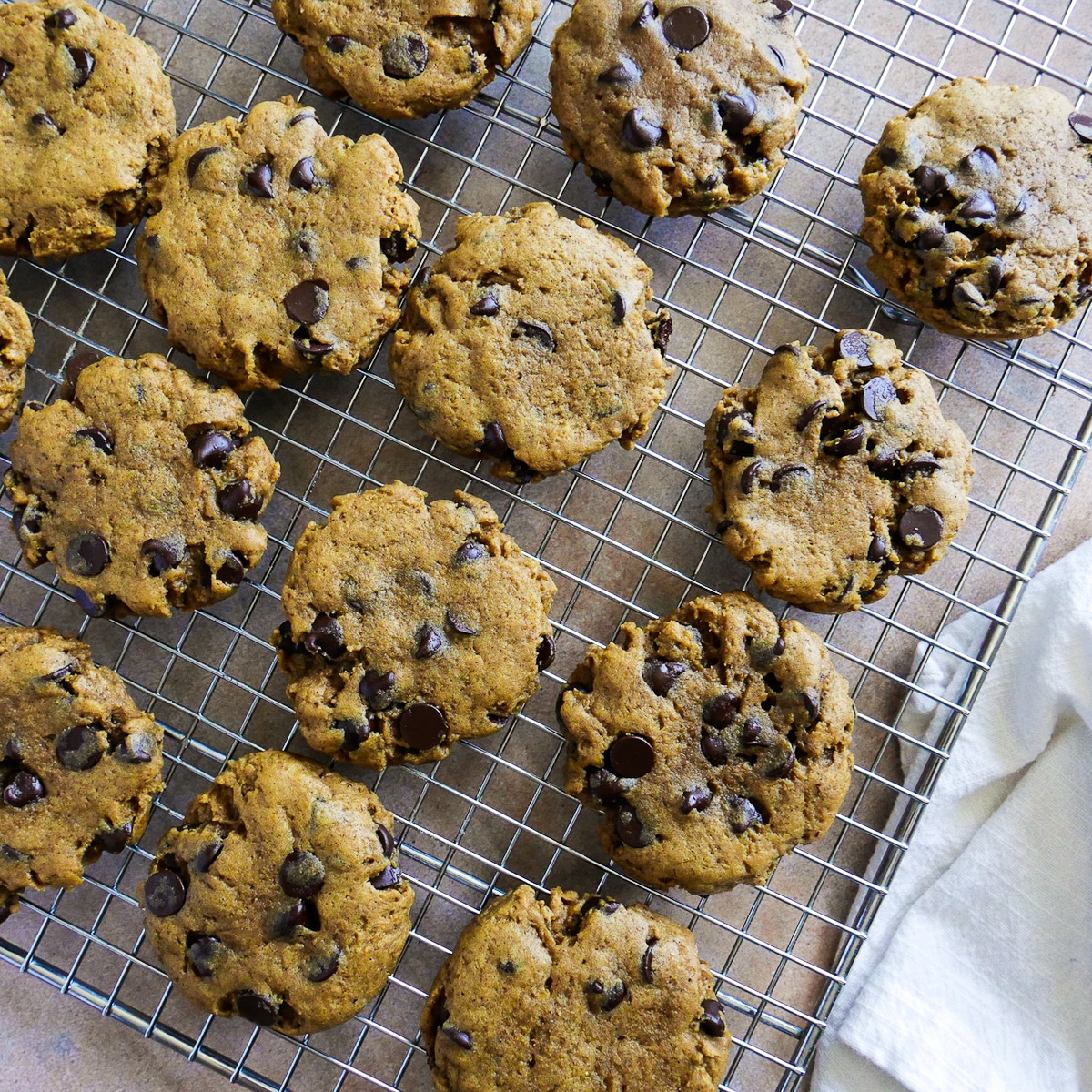 Cookies arranged on cooling rack with a white napkin on the side. 