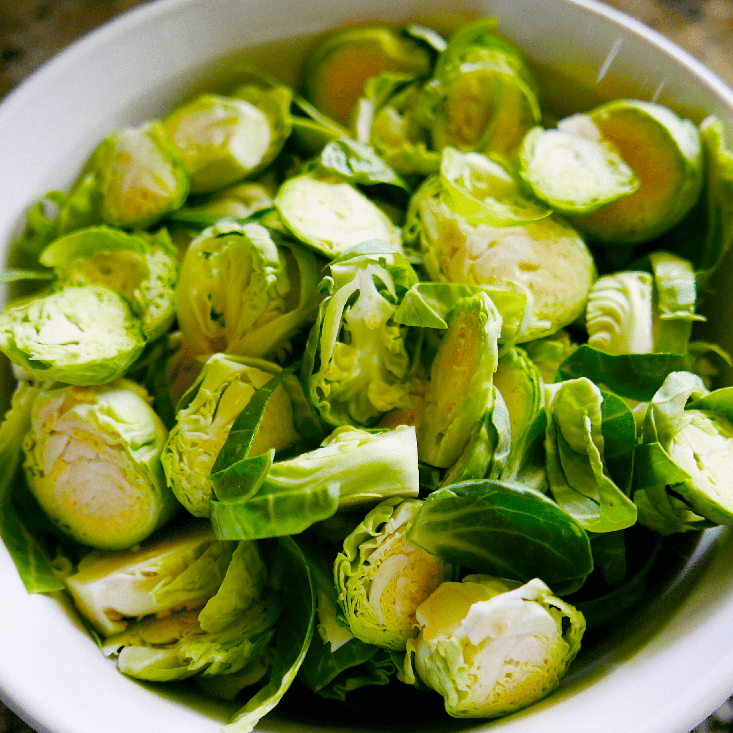 Trimmed and halved Brussels sprouts in a mixing bowl. 