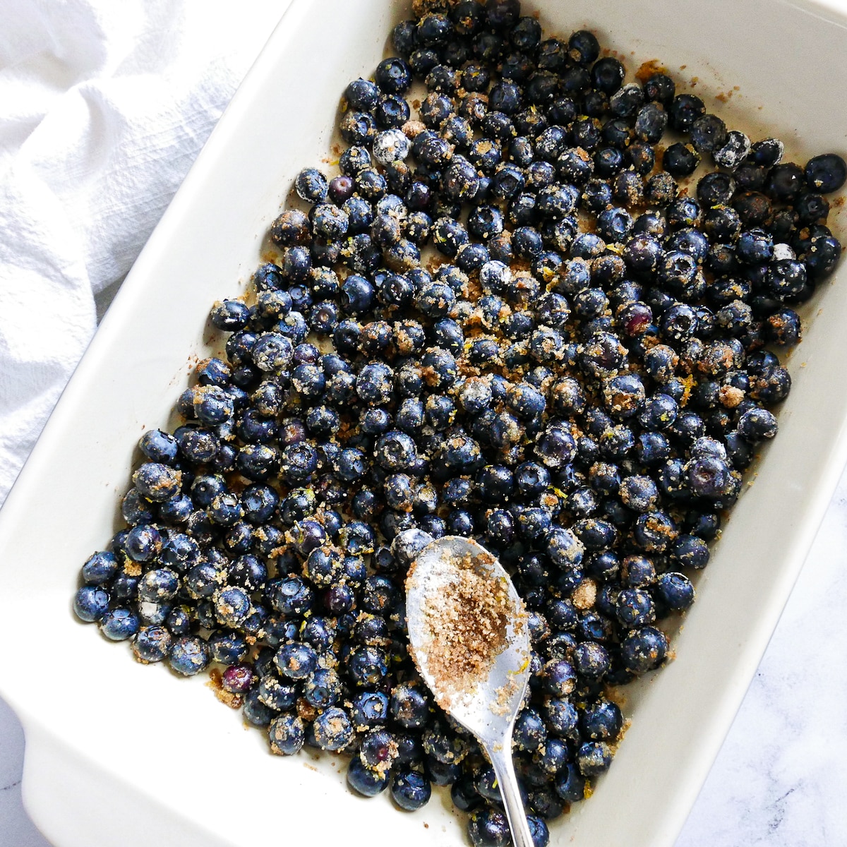 blueberries, sugar, cornstarch, and lemon tossed in a prepared baking dish.