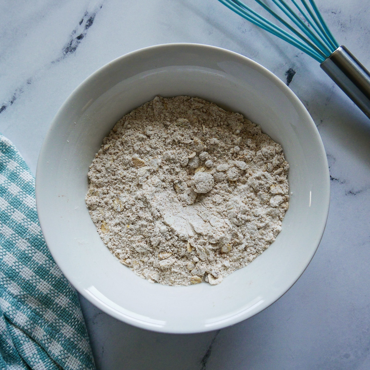 Flour, oats, brown sugar, baking powder, cinnamon, and salt combined in a small white bowl.