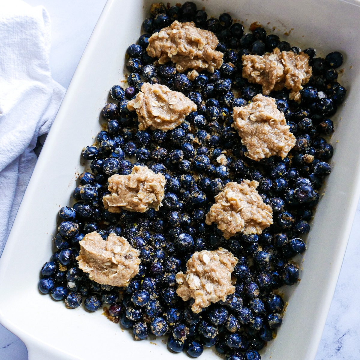 biscuit batter placed on top of blueberry filling in a baking dish.