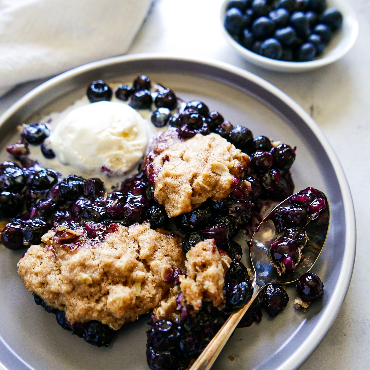 vegan cobbler on a plate with melting ice cream and spoon.