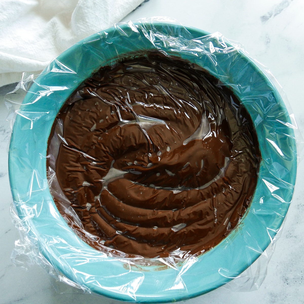 plastic wrap placed on top of chocolate pudding.