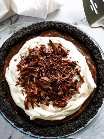 chocolate cream pie placed on a table with a pie server and napkin.