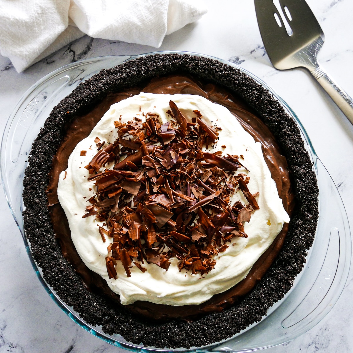chocolate-pie-with-server.jpg chocolate cream pie placed on a table with a pie server and napkin.