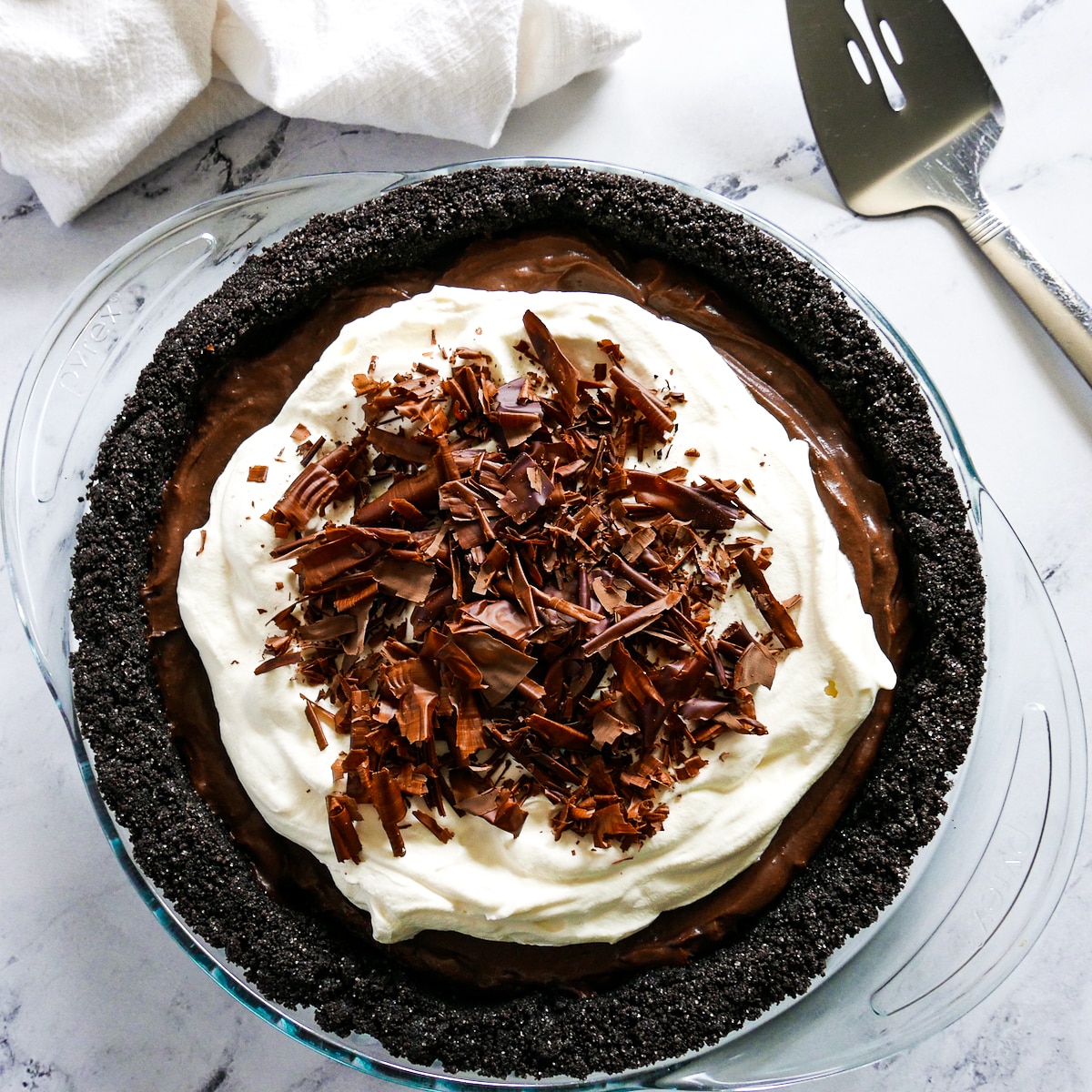 no bake chocolate pie placed on a table with a pie server and napkin.