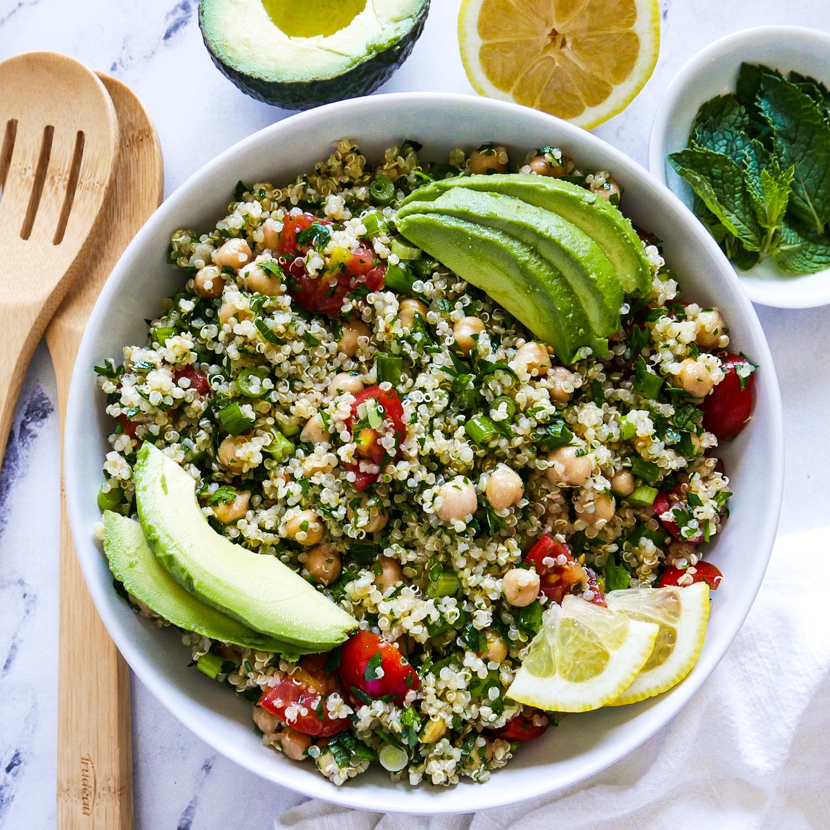 Quinoa tabbouleh garnished with avocado, lemon, and chopped mint.