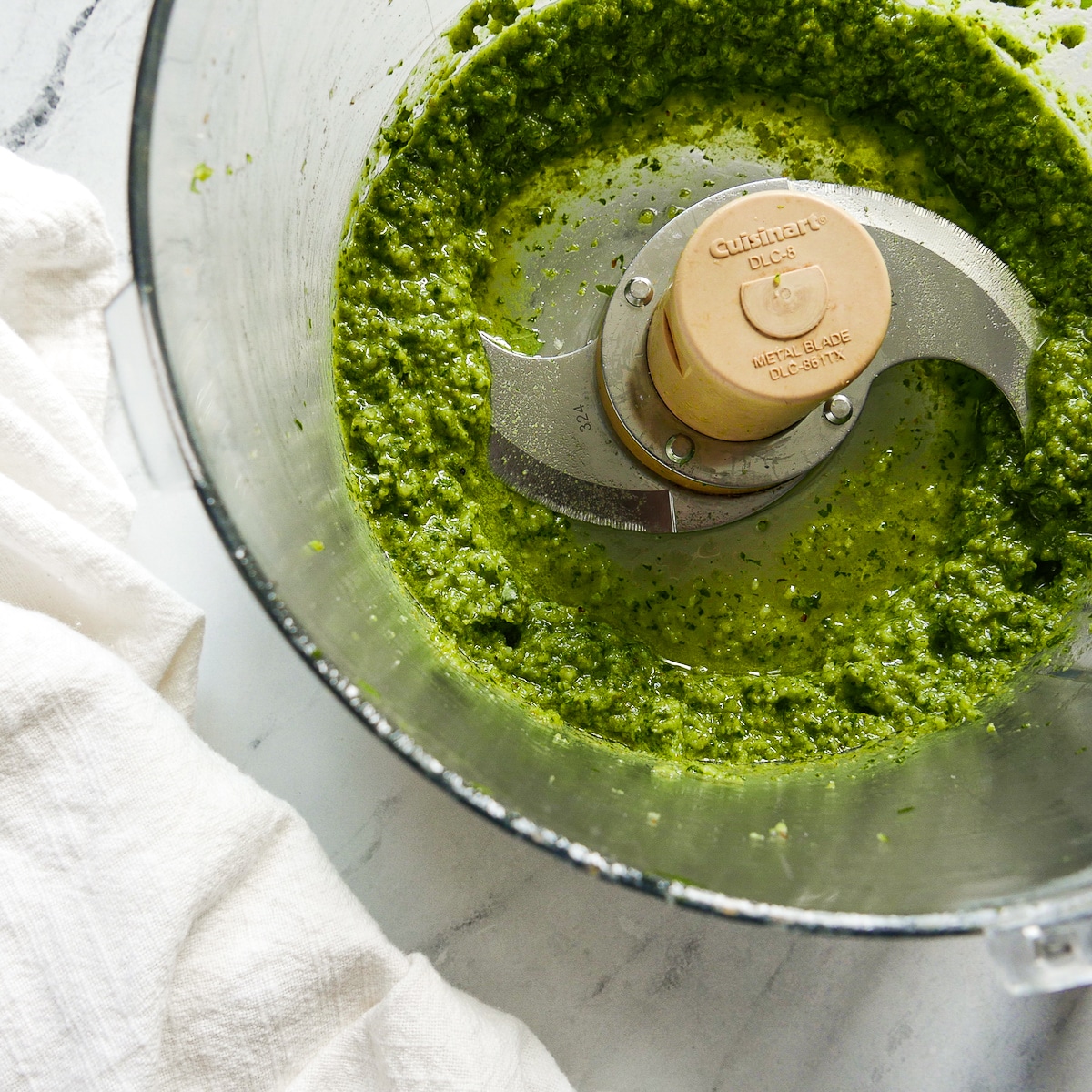 walnut pesto in a food processor with a white napkin on the side. 