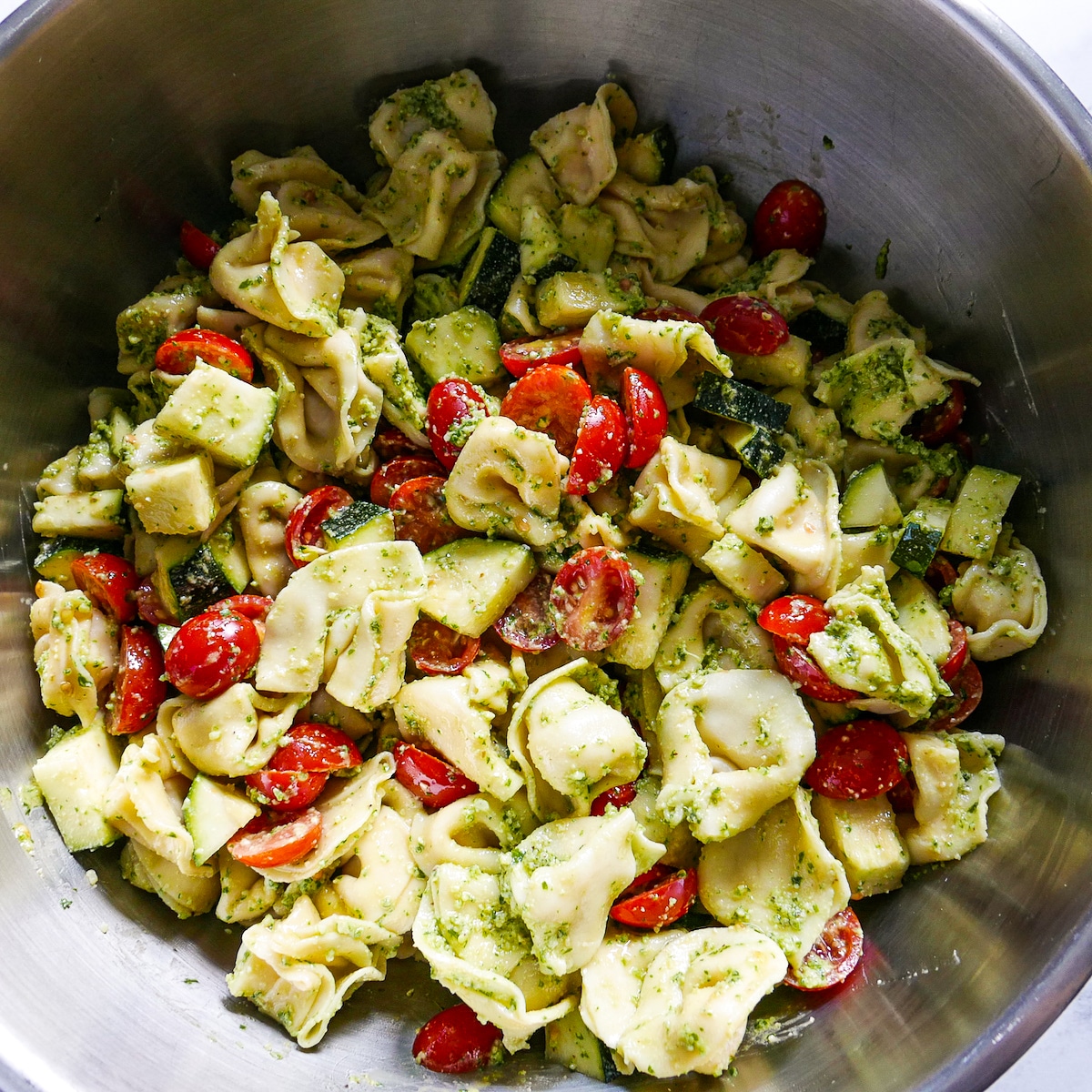 pasta salad mixed with walnut pesto in large bowl.