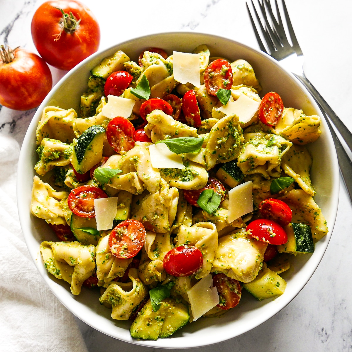 bowl of vegetarian tortellini salad with two forks on the side.