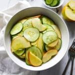 apple cucumber salad assembled in a bowl with two forks and napkin on the side.