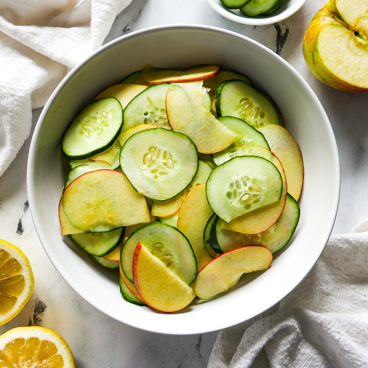 salad with sliced apple and cucumber on the side with a napkin.