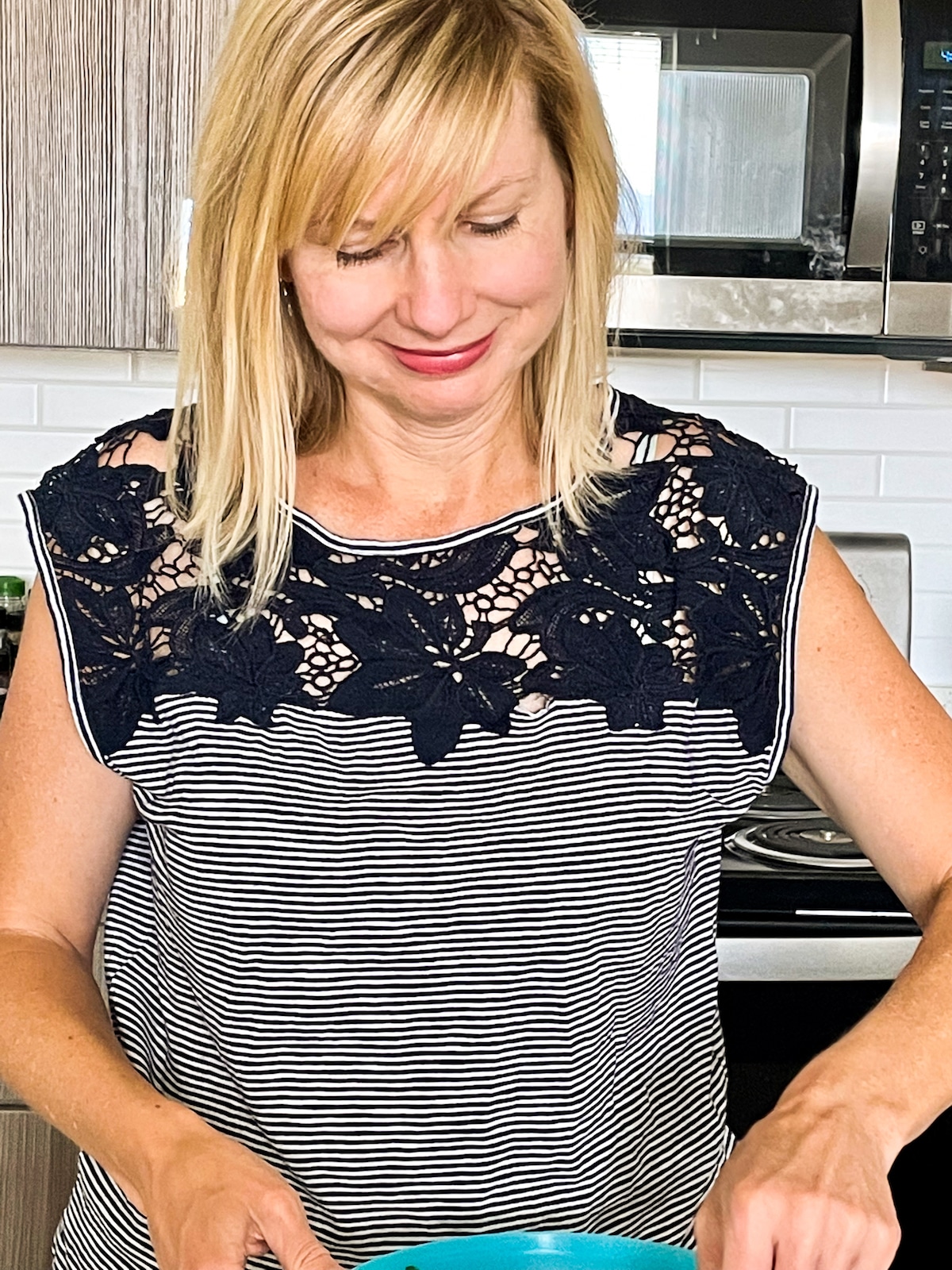 woman stirring bowl of salad in her kitchen.