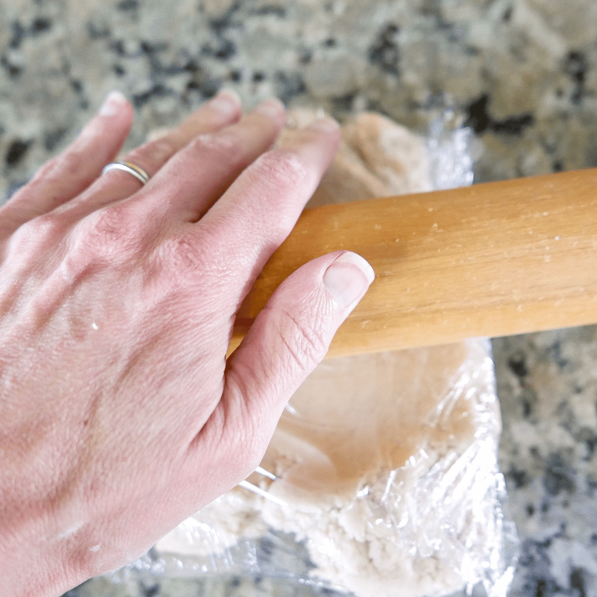 white hand rolling out cookie dough with rolling pin.