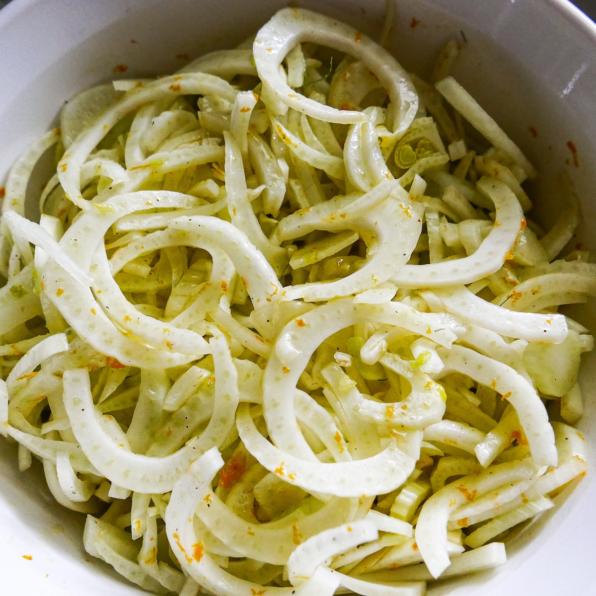 fennel tossed with salad ingredients in a large mixing bowl.