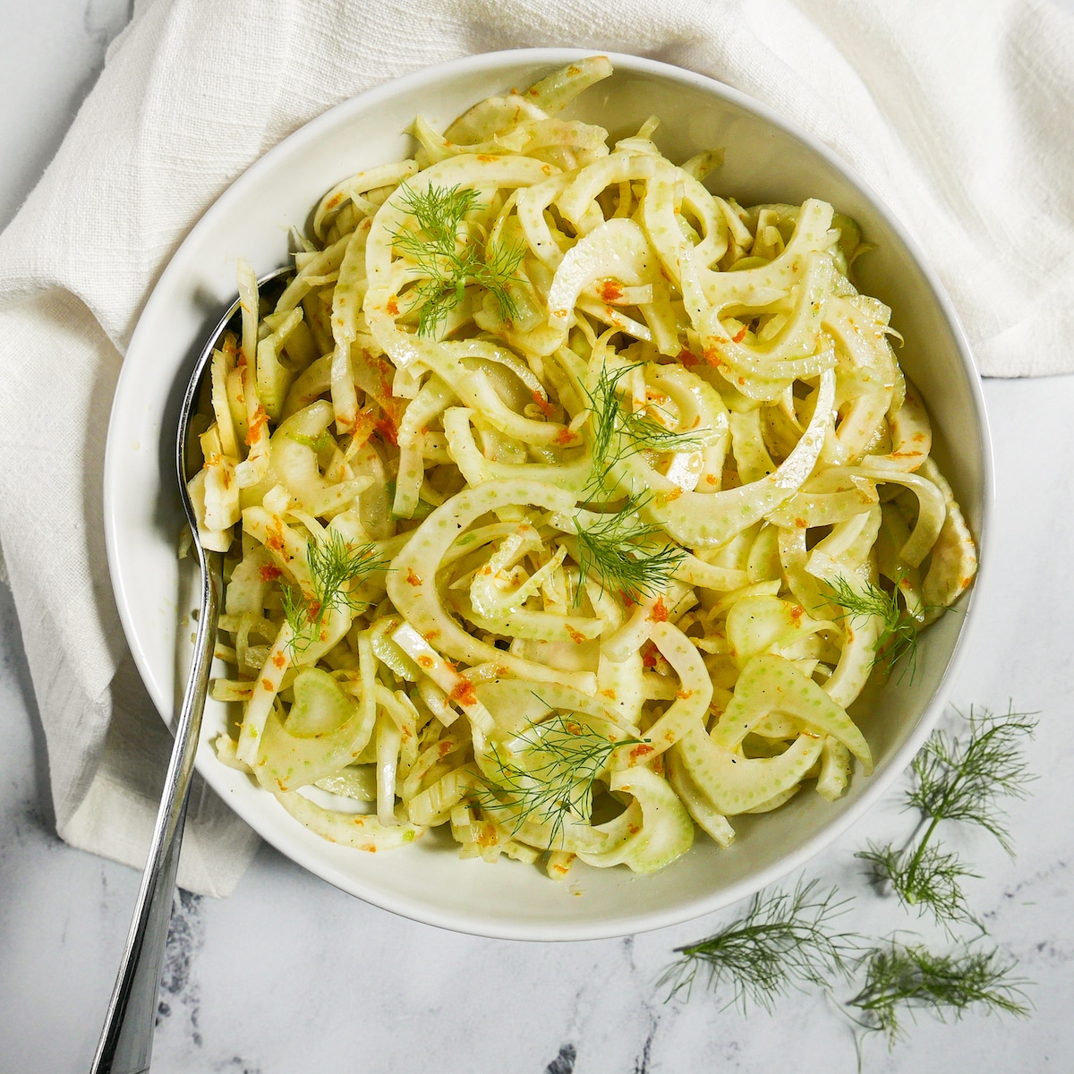 fennel salad garnished with fennel fronds and resting on a white napkin.