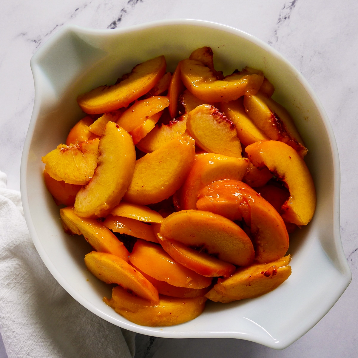 peeled and sliced peaches in a mixing bowl.