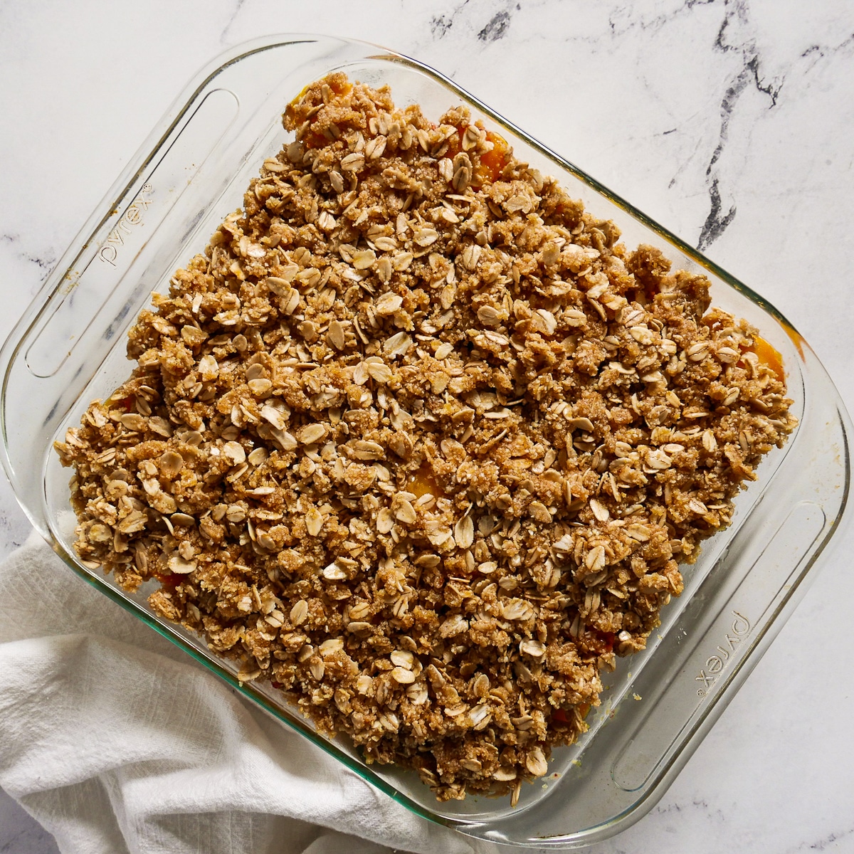 peach filling and crisp topping assembled in baking dish.