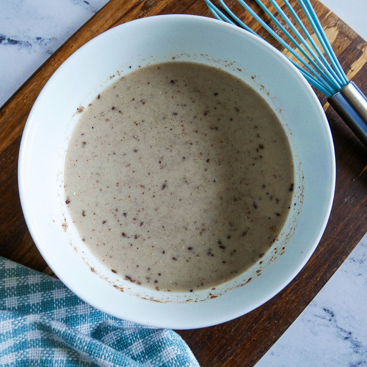 ingredients mixed together in a white bowl with a whisk in the background. 