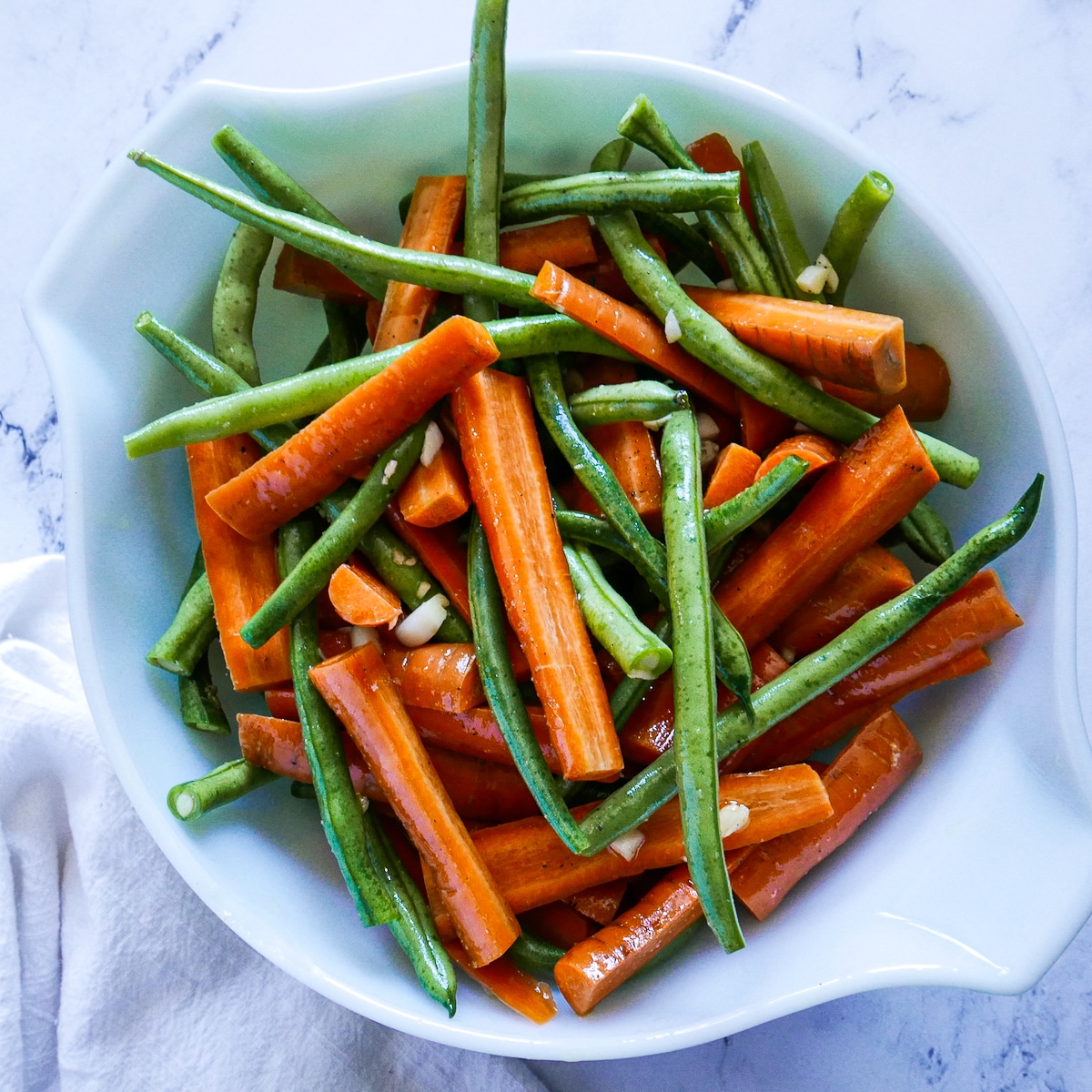 cut vegetables tossed with olive oil, garlic, salt, and pepper in a mixing bowl.