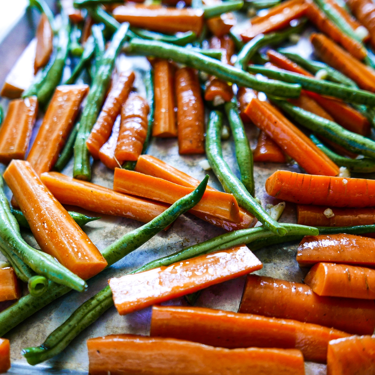 coated vegetables spread out onto a baking sheet.