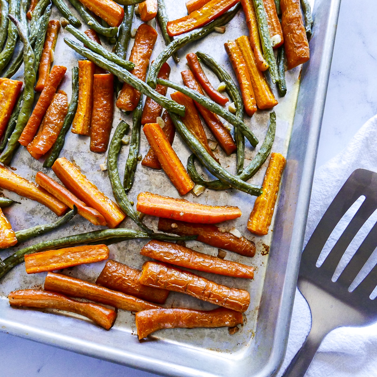 roasted vegetables on a baking sheet with a spatula.