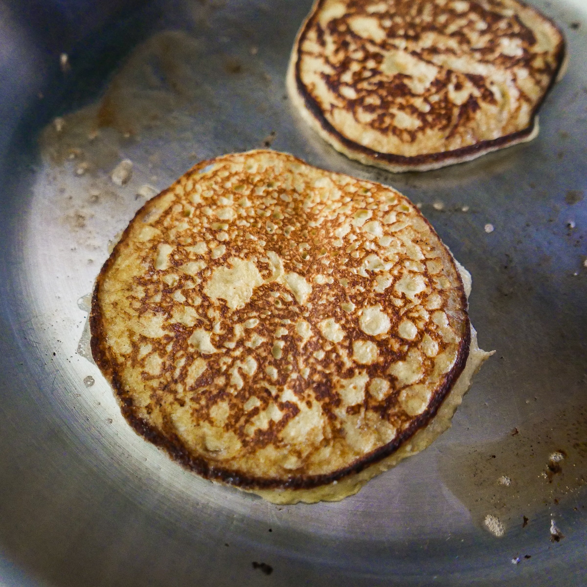 flipped-pancakes-in-skillet.jpg flipped golden brown pancakes in a skillet.