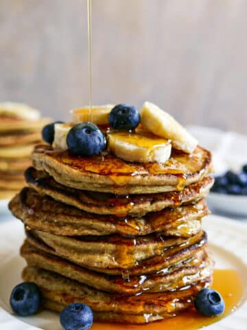 stack of banana oat pancakes with syrup being poured on top.