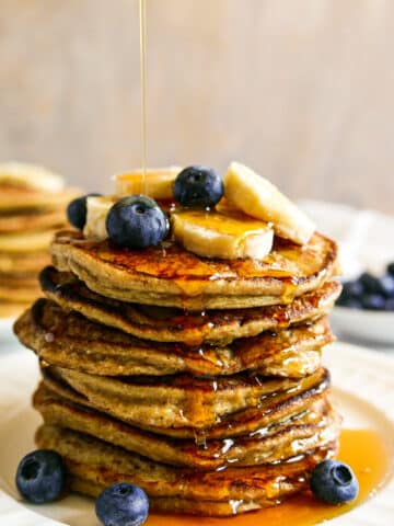 stack of banana oat pancakes with syrup being poured on top.