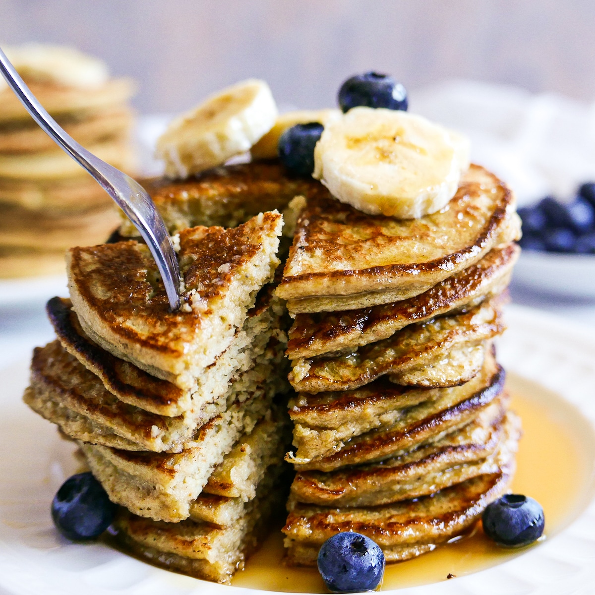 fork-taking-bite-of-pancakes.jpg fork pulling at a large bite of pancakes from plate.