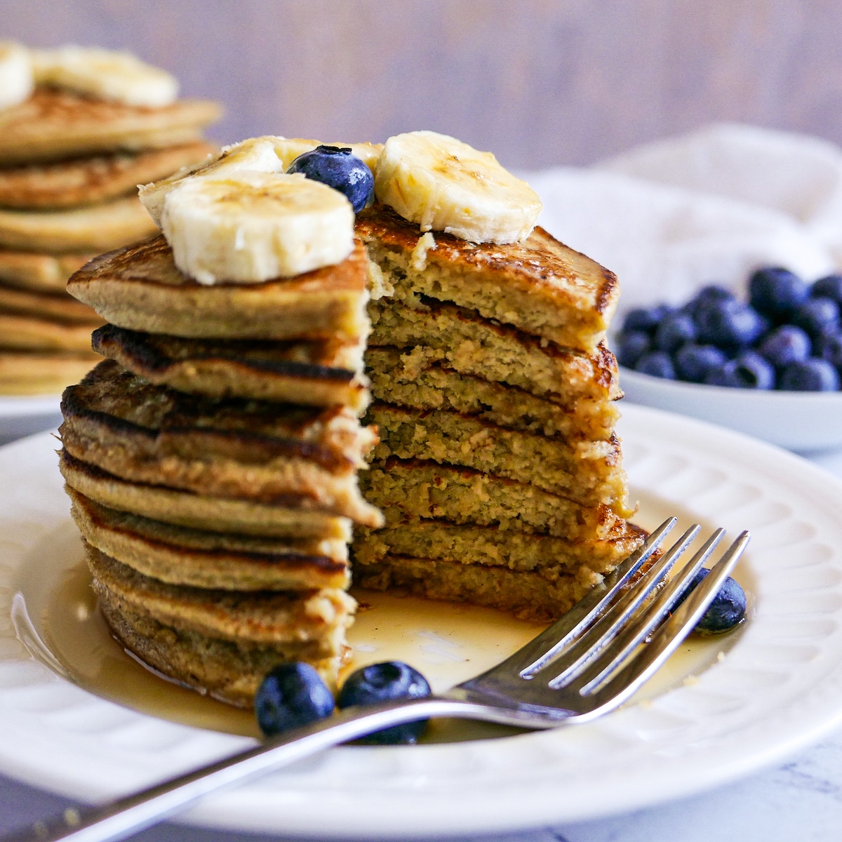 cut-pancakes-with-fork.jpg stack of pancakes that have been cut into with a fork resting on the plate.