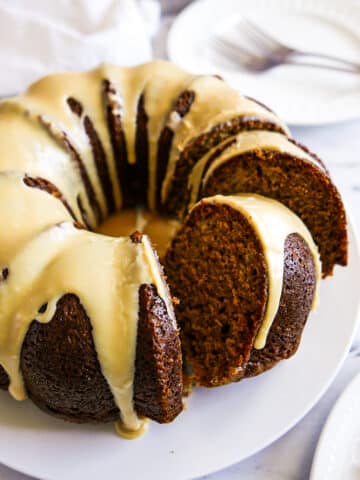 frosted and sliced bundt cake on a white platter.