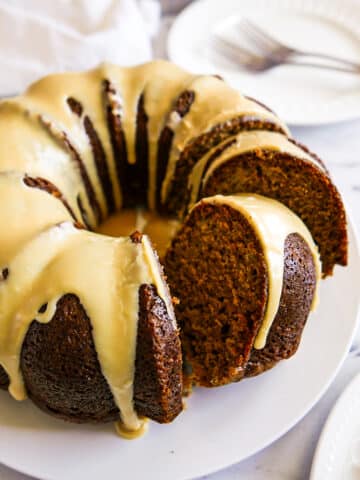 frosted and sliced bundt cake on a white platter.