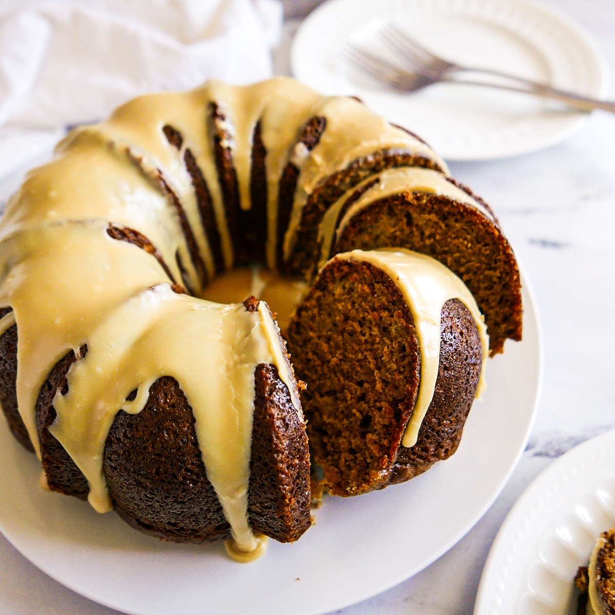 frosted and sliced bundt cake on a white platter.