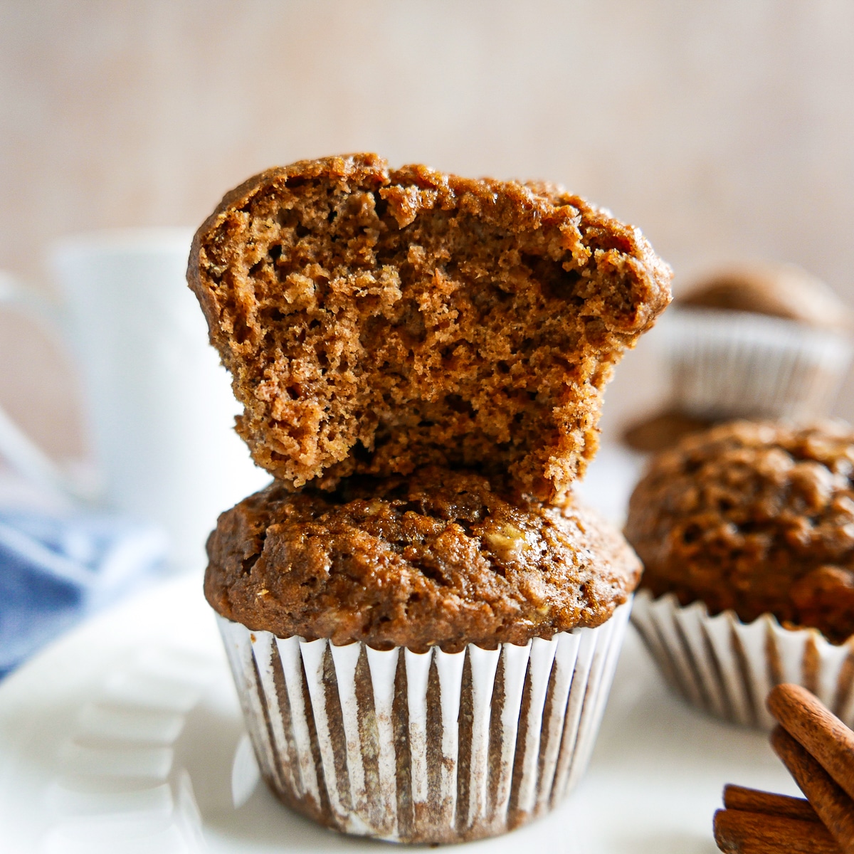 two muffins stacked with cinnamon sticks on the side.