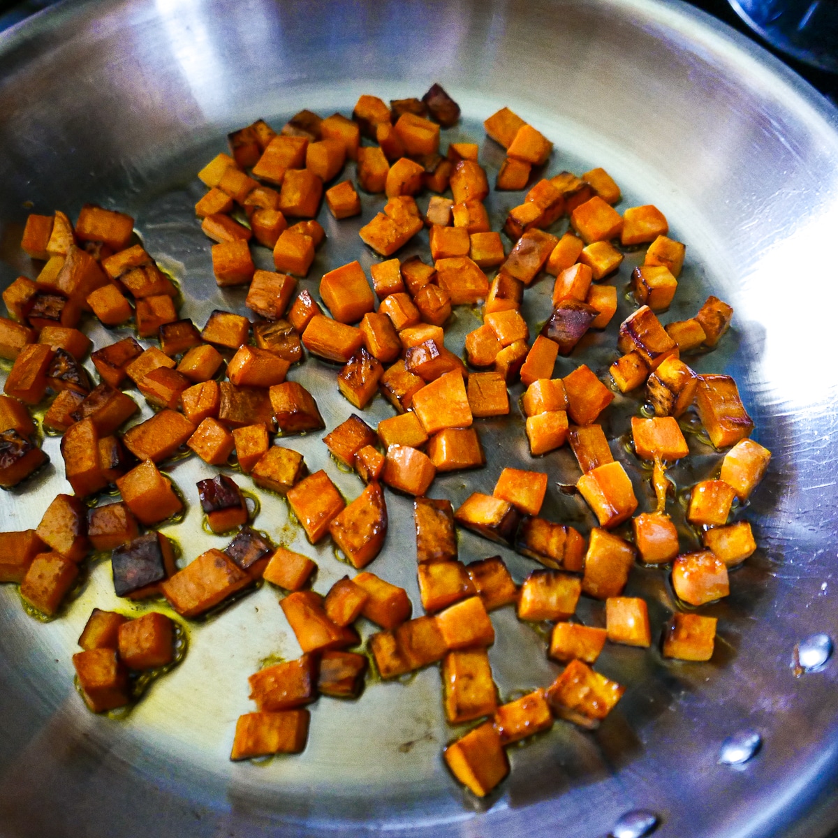 sweet potatoes being cooked in a large skillet.