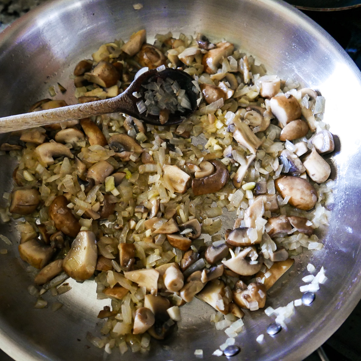 mushrooms and garlic added to cooked onion mixture in a skillet.
