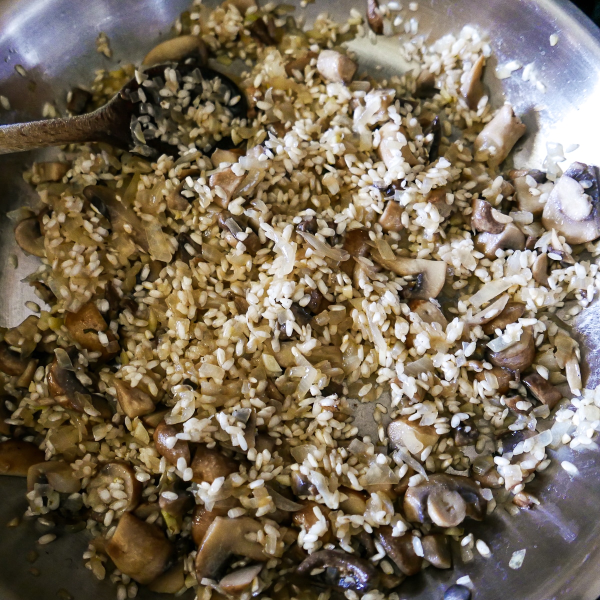 arborio rice stirred into onion mixture in a skillet.