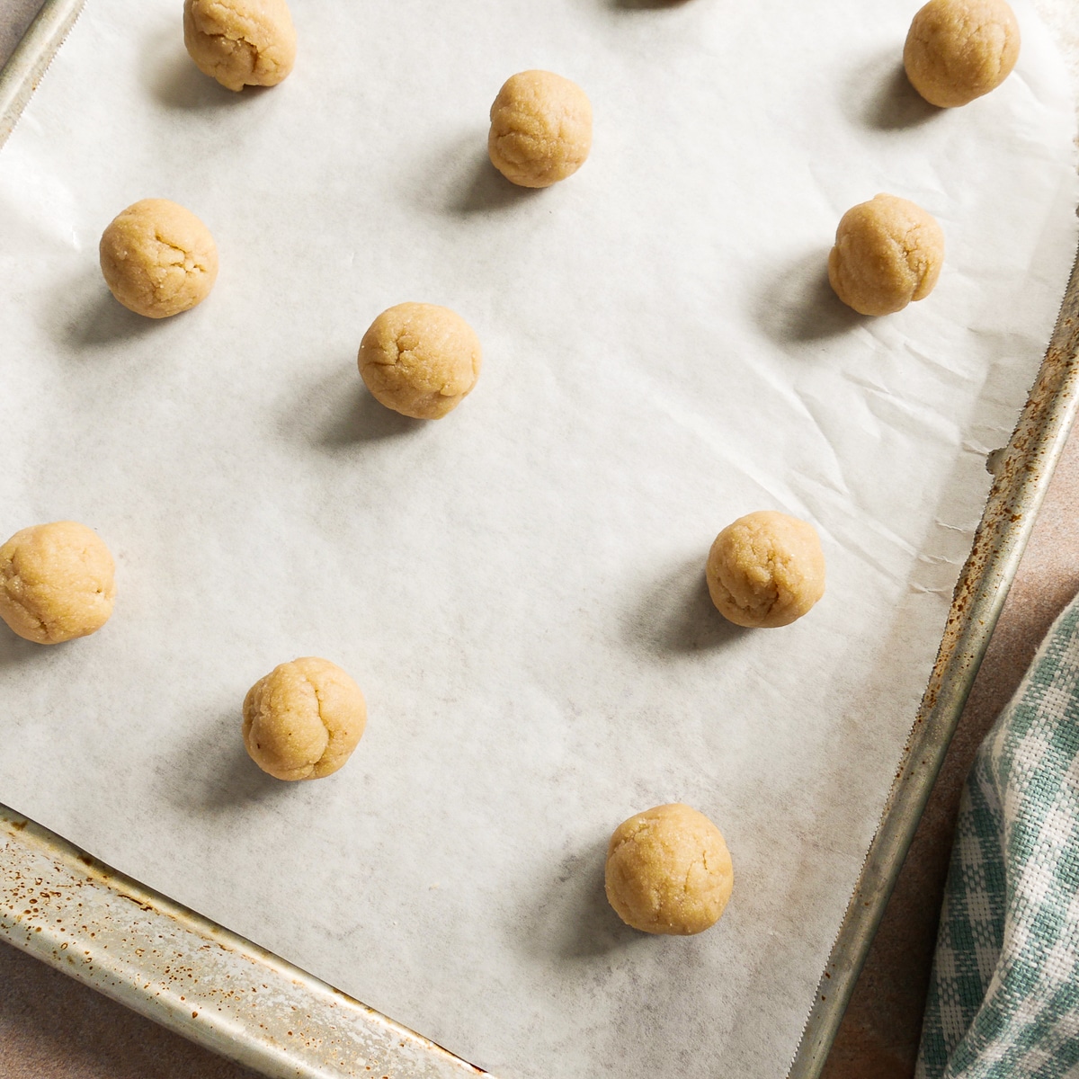 cookie dough rolled into balls and placed on a parchment-lined baking sheet.