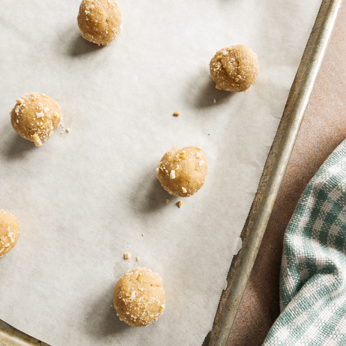 balls dipped in crushed almonds and placed on a baking sheet.