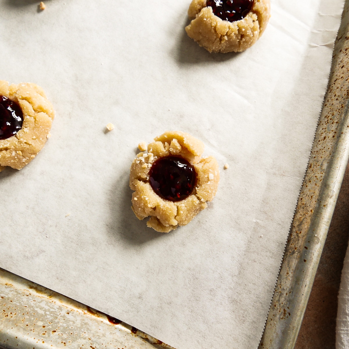 cookie dough filled with raspberry jam on a baking sheet.