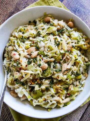 bowl of creamy braised white beans and leeks with a spoon.