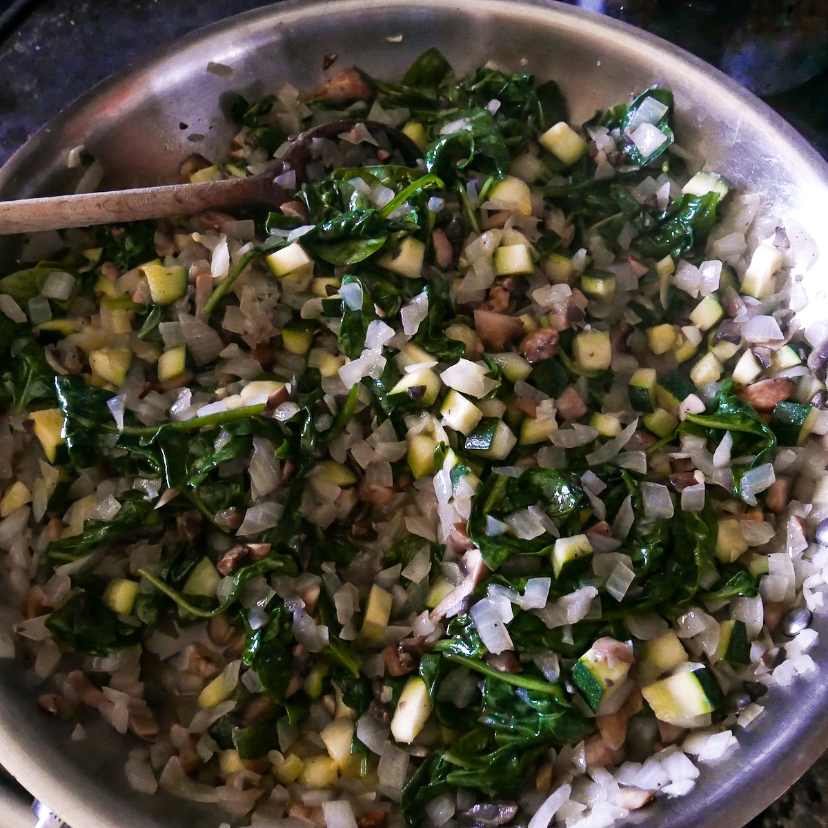 spinach-added-to-vegetables.jpg spinach added to vegetables cooking in a skillet.