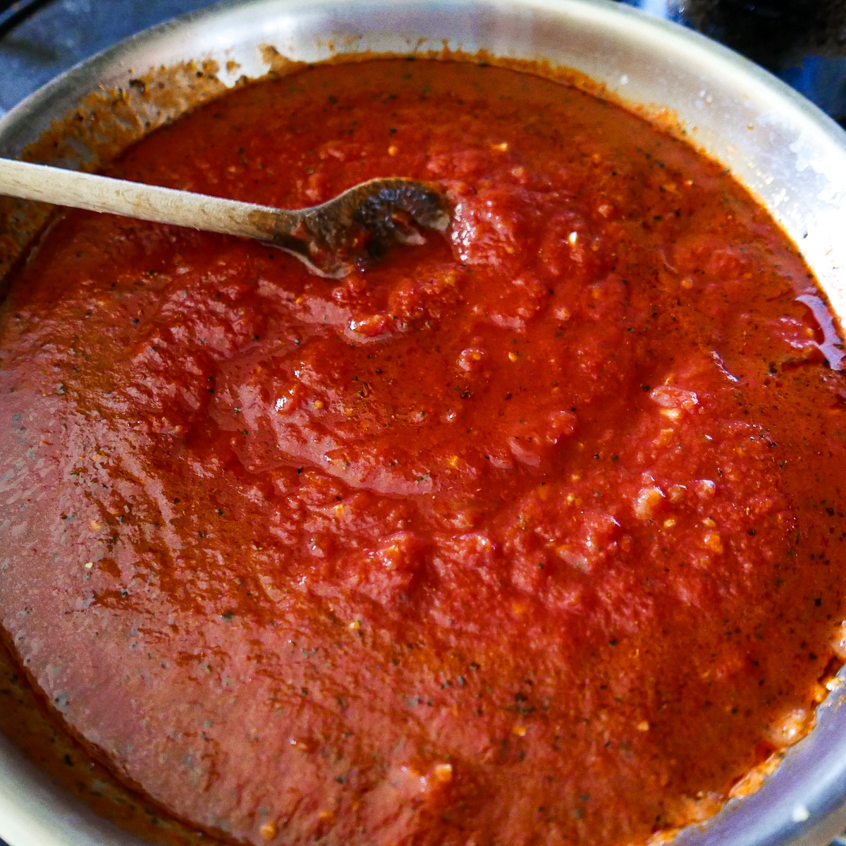 tomato-sauce-cooking.jpg tomato paste, crushed tomatoes, and water added to garlic and herbs mixture in skillet.