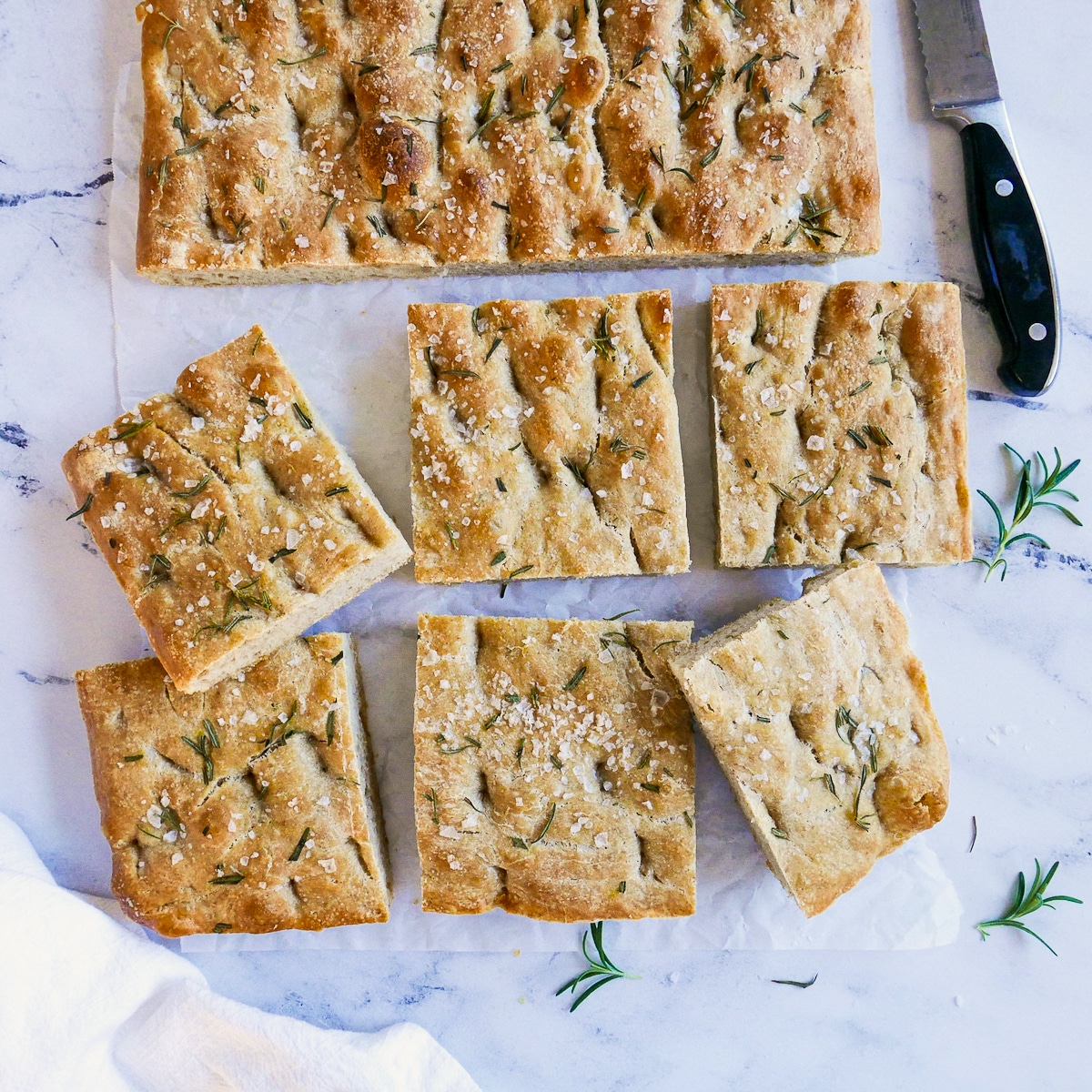 focaccia sliced into squares on parchment paper.