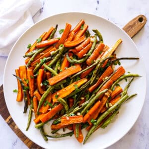 Platter of roasted carrots and green beans drizzled with balsamic.