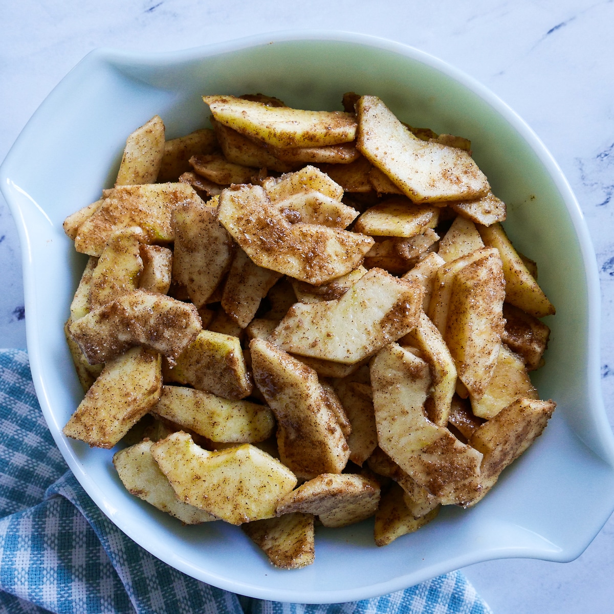 apples tossed with sugar and spice mixture in a bowl.