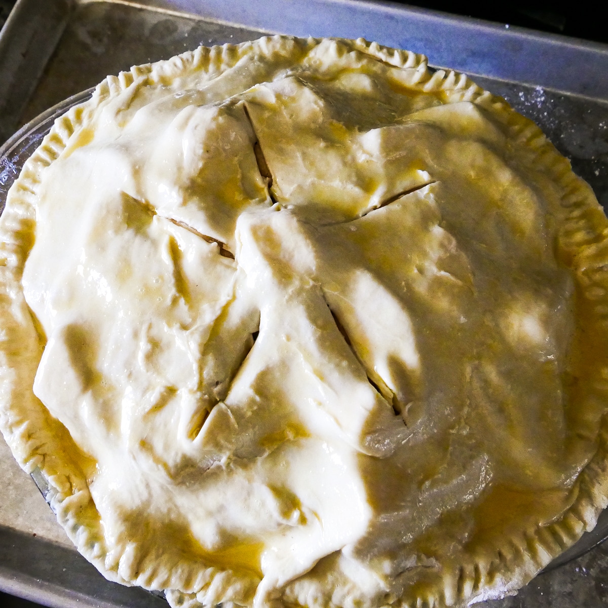 apple pie topped with puff pastry with slits cut into it.