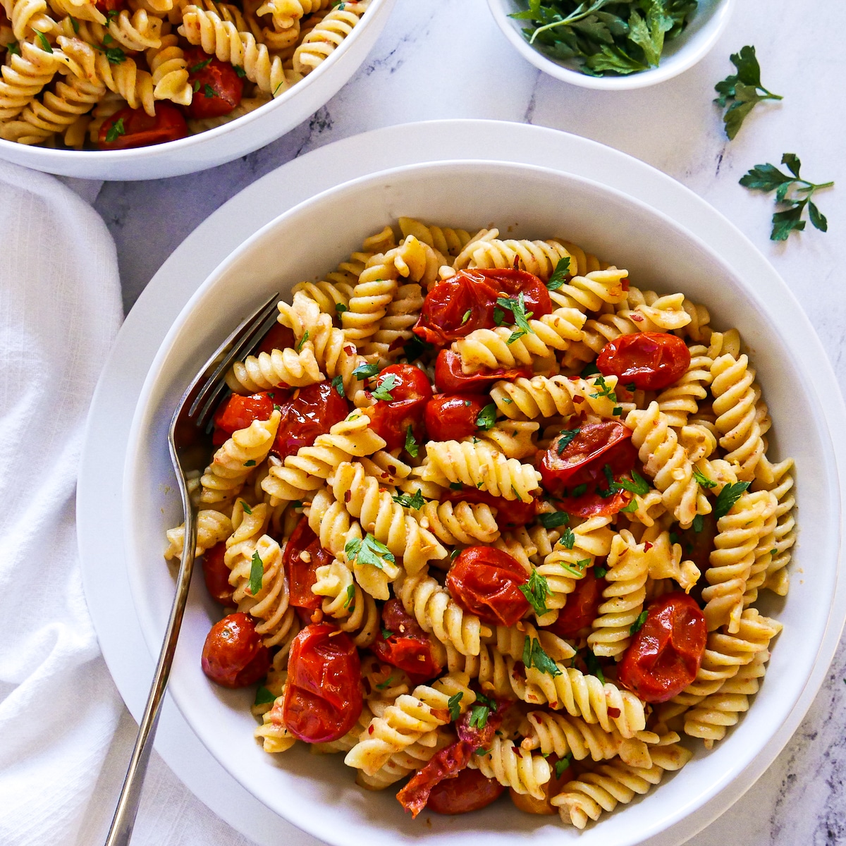 bowl of creamy tahini pasta with a fork and white napkin.